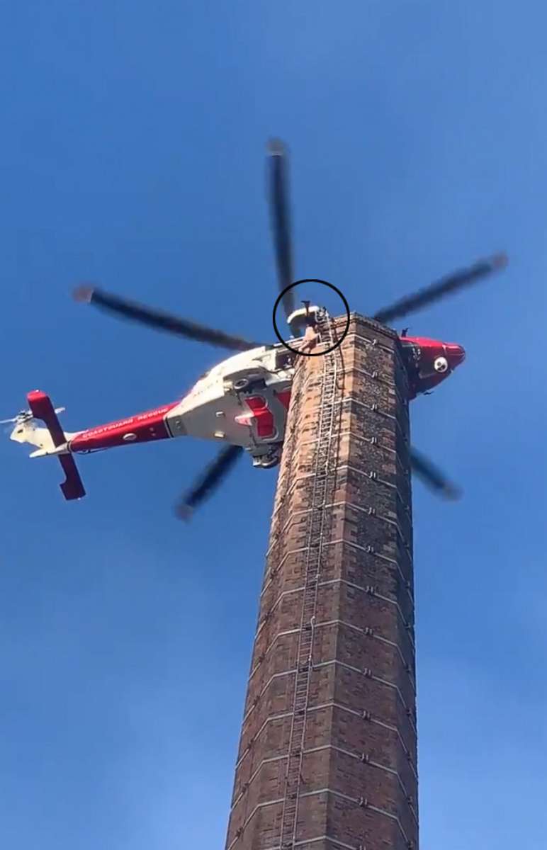 PHOTO: A man dangles from 290 foot smoke stack as an emergency helicopter tries to get close enough to rescue him in northern England.