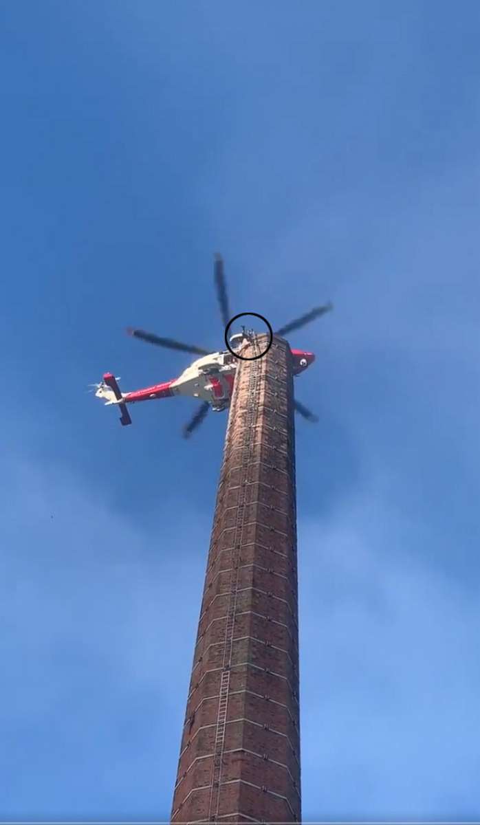 PHOTO: A man dangles from 290 foot smoke stack as an emergency helicopter tries to get close enough to rescue him in northern England.