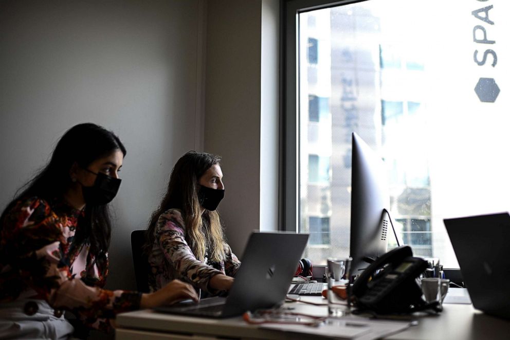 PHOTO: Two women wearing protective facemasks work in a co-working office at the business district of La Defense west of Paris, Oct. 7, 2020, as the country faces a new wave of infections to the Covid-19 (the novel coronavirus).