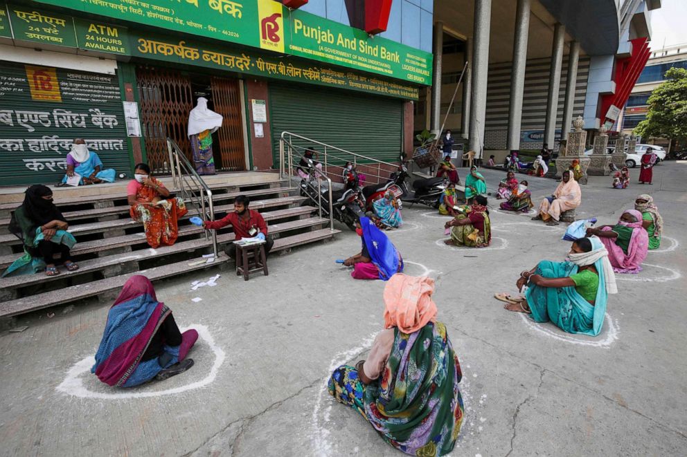 PHOTO: Women maintain social distancing outside a bank as they wait to collect their pension during a government-imposed nationwide lockdown as a preventive measure against the spread of the novel coronavirus in Bhopal, India, on April 15, 2020.
