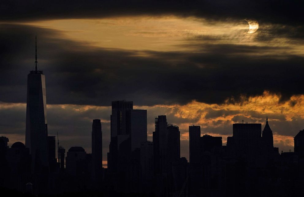 PHOTO: The sun is partially eclipsed as it rises over lower Manhattan in New York, June 10, 2021.