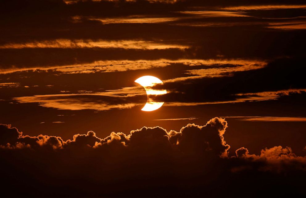 PHOTO: A partial solar eclipse rises behind clouds, June 10, 2021, in Arbutus, Md.