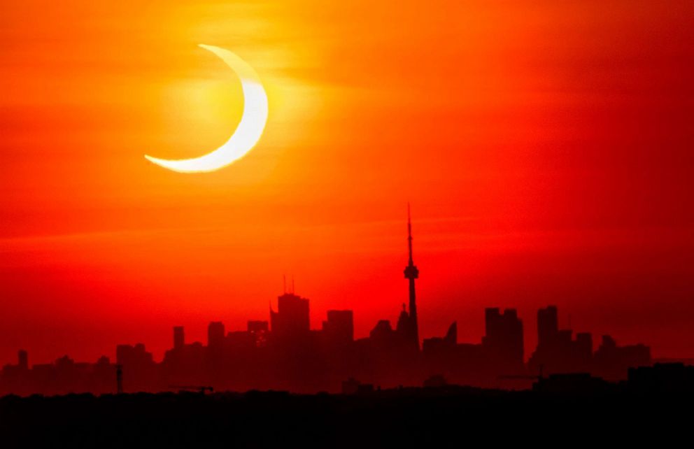 PHOTO: An annular solar eclipse rises over the skyline of Toronto, June 10, 2021.