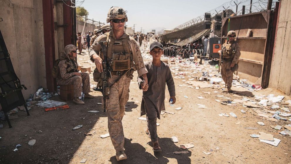 PHOTO: A U.S. Marine with the Special Purpose Marine Air-Ground Task Force-Crisis Response-Central Command (SPMAGTF-CR-CC) escorts a child to his family during an evacuation at Hamid Karzai International Airport in Kabul, Aug. 24, 2021.