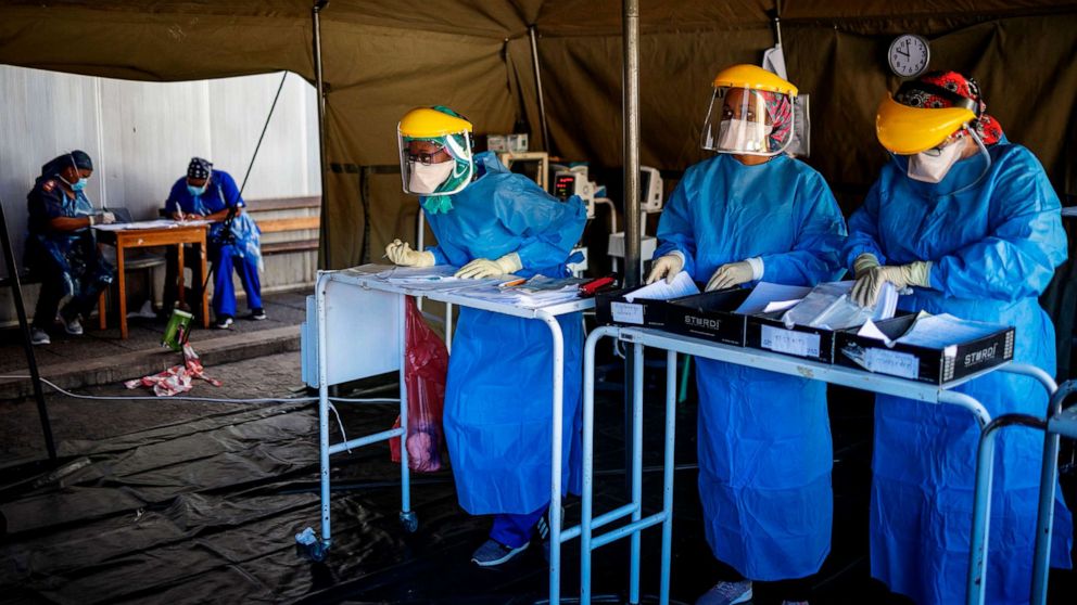 PHOTO: A health worker speaks with another health worker before performing tests for COVID-19 coronavirus at the screening and testing tents set up at the Charlotte Maxeke Hospital in Johannesburg, South Africa, on April 15, 2020.