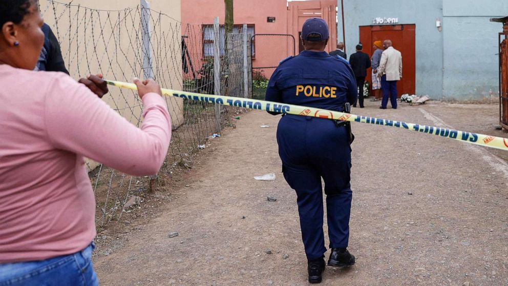 PHOTO: South African Police Services members use a tape to cordon off the entrance of a township pub in southern city of East London on July 5, 2022, after the death of 21 teenagers in the establishment.