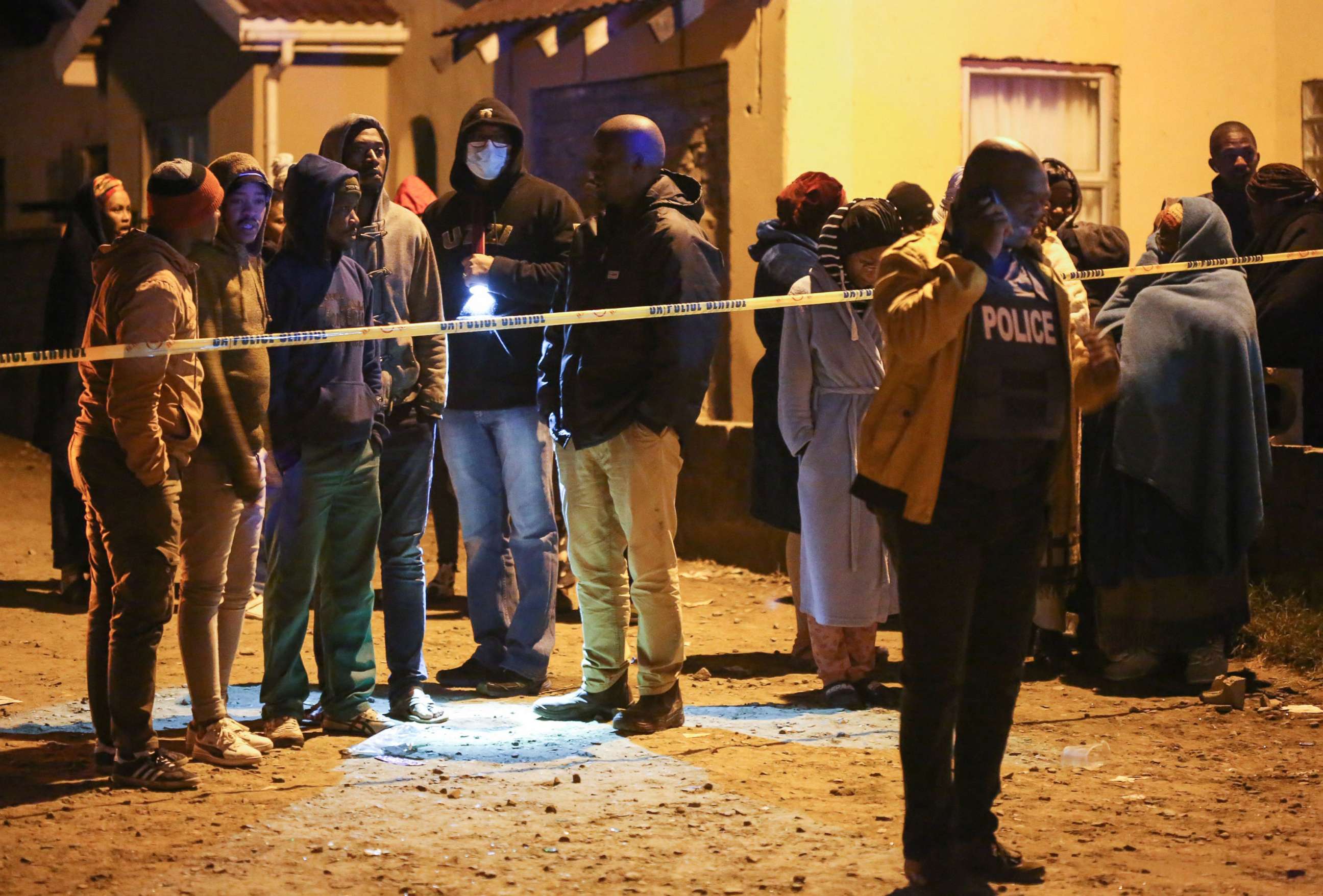 PHOTO: People, including family members, wait for news outside a township pub in South Africa's southern city of East London on June 26, 2022, after 20 teenagers died.
