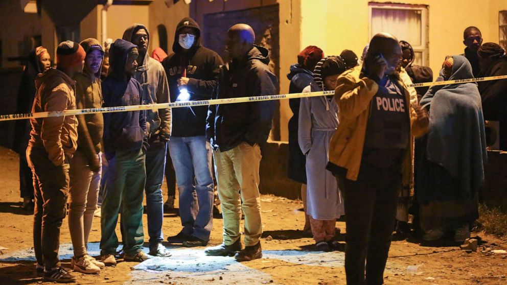 PHOTO: People, including family members, wait for news outside a township pub in South Africa's southern city of East London on June 26, 2022, after 20 teenagers died.