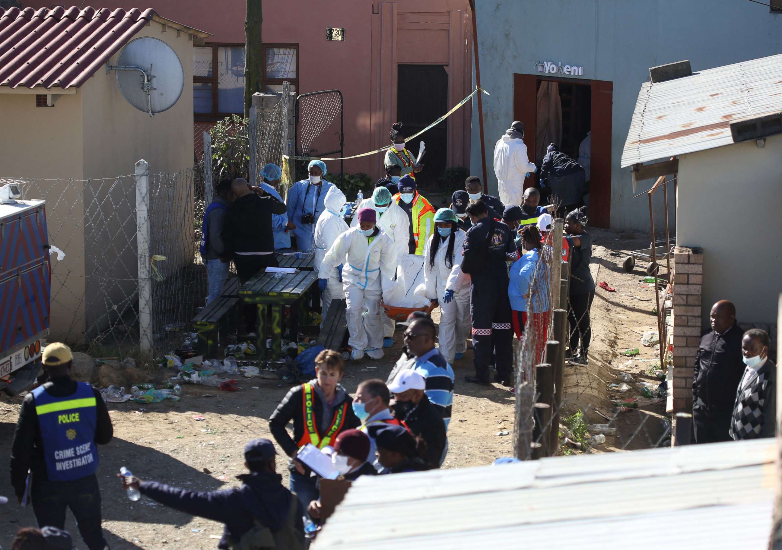 PHOTO: Forensic personnel carry a body out of a township pub in South Africa's southern city of East London on June 26, 2022, after 20 teenagers died.