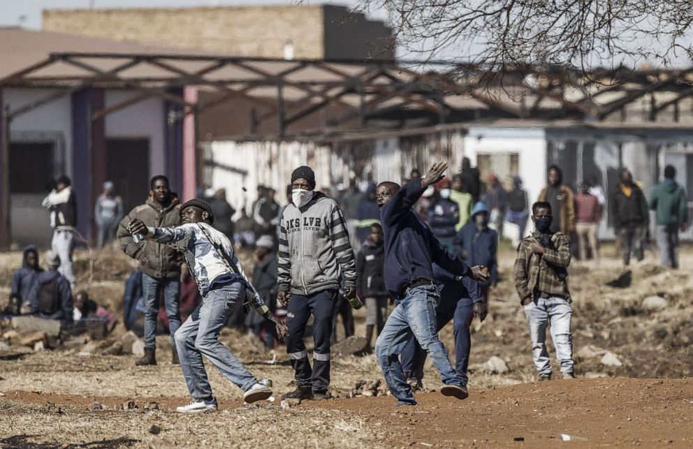 PHOTO: Residents throw rocks as they confront police officers at the entrance of a partially looted mall in Vosloorus, on July 13, 2021.