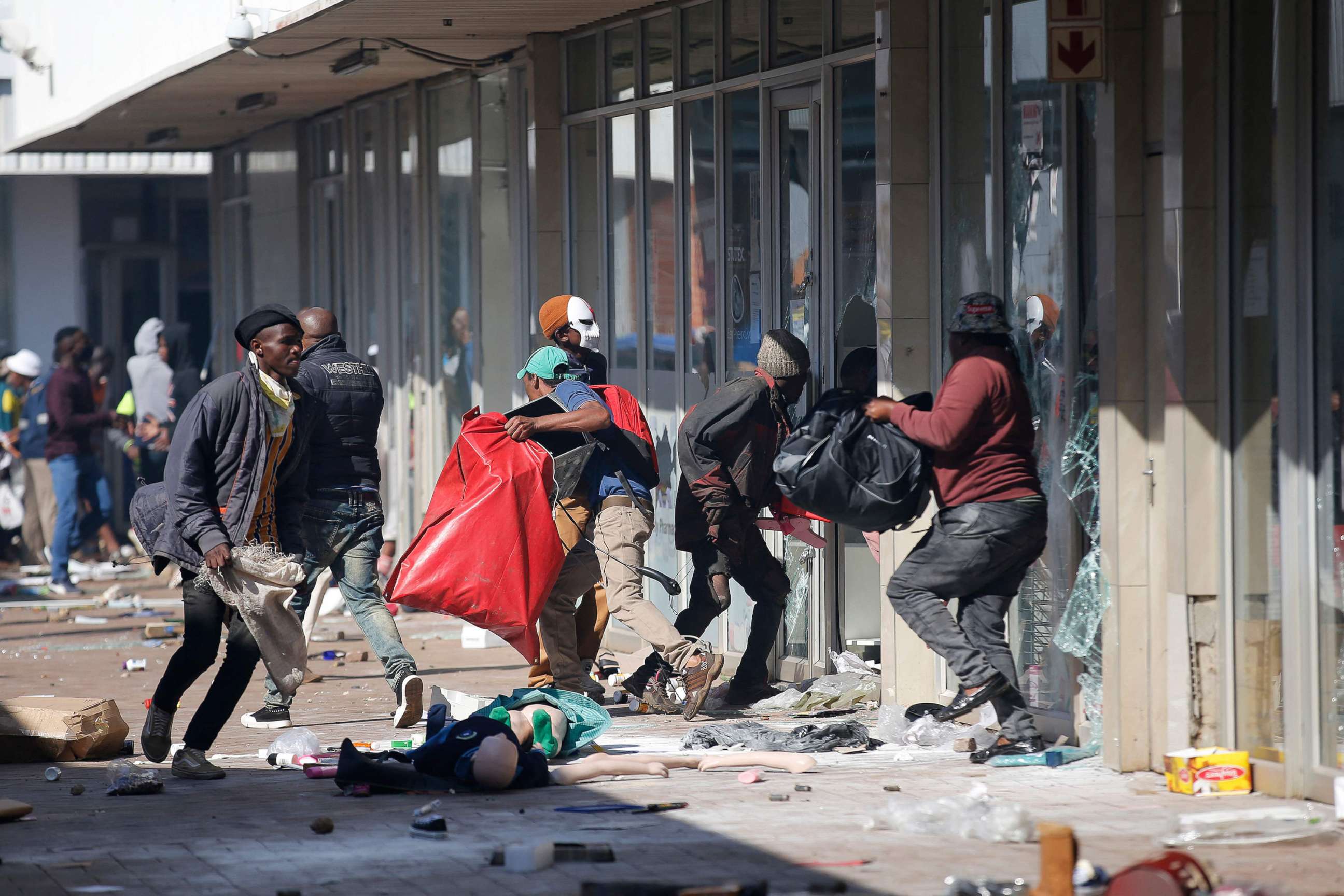 PHOTO: People carry goods as they loot and vandalize the Lotsoho Mall in Katlehong township, east of Johannesburg, on July 12, 2021.