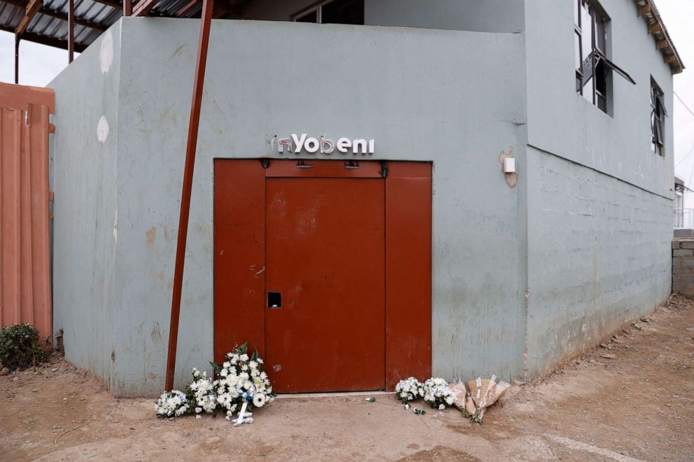 PHOTO: Flowers are seen at the entrance of a township pub in southern city of East London on July 5, 2022, after the death of 21 teenagers in the establishment. 