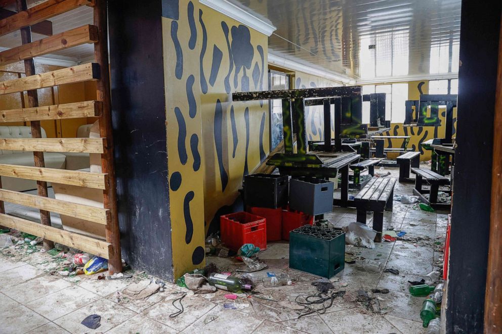 PHOTO: Empty alcohol bottles, crates, wooden chairs and tables are seen inside a township pub in southern city of East London on July 5, 2022, after the death of 21 teenagers in the establishment. 