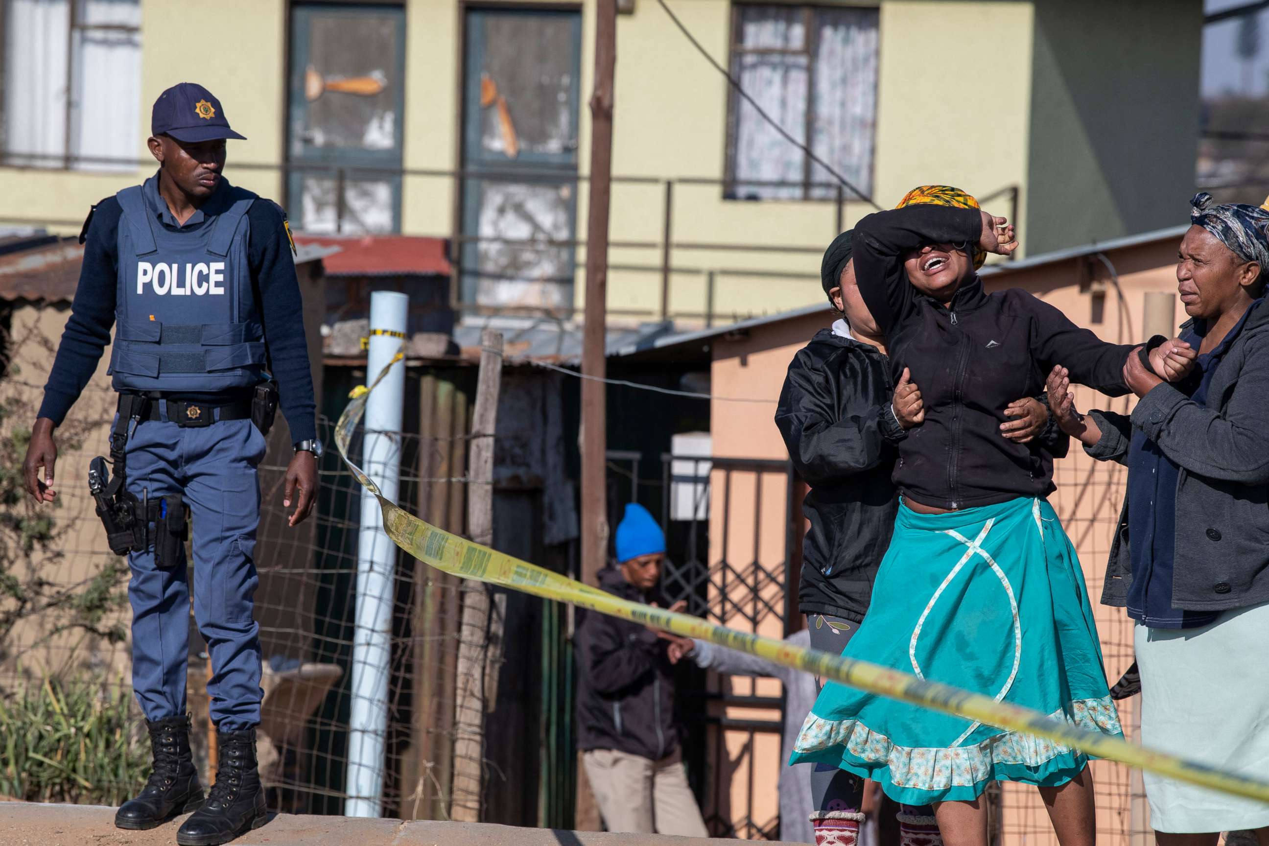 PHOTO: A relative of one of the victims of a bar shooting cries as south African Police Service officers refuse to let her cross the police barrier and enter the crime scene in Soweto, South Africa, on July 10, 2022.