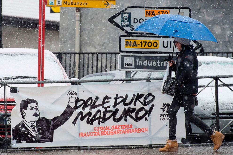 PHOTO: A woman walks under the snow past a banner in the Spanish Navarra village of Leitza, Jan. 30, 2019.