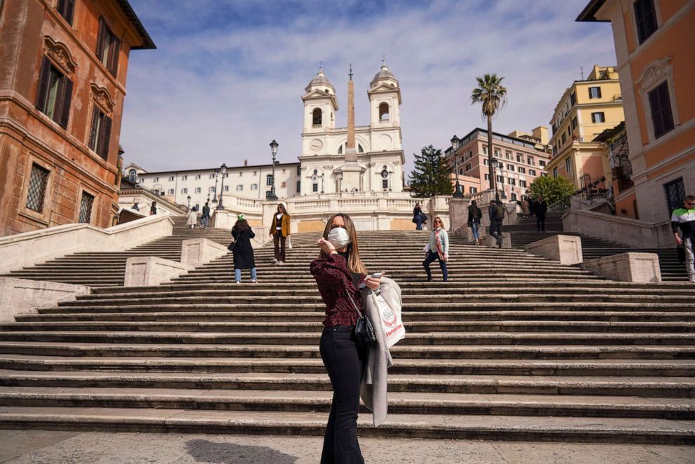 PHOTO: A woman wearing a mask poses for photos at the bottom of the Spanish Steps, in Rome, March 5, 2020, during the coronavirus outbreak.