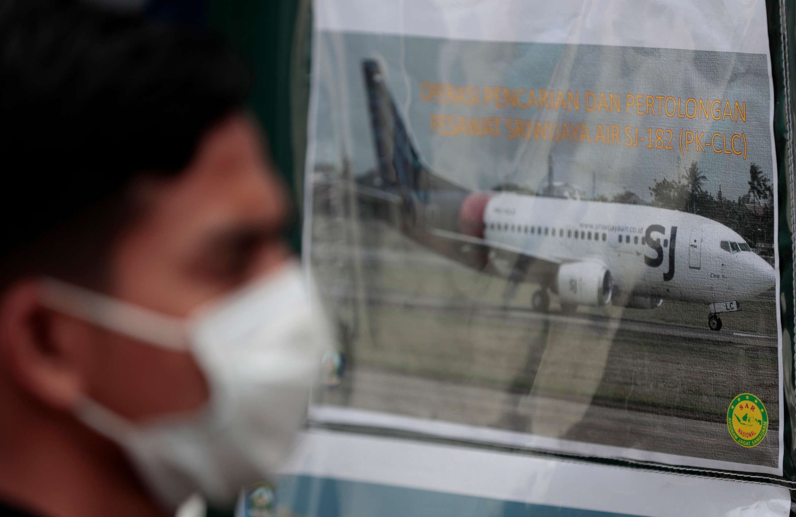 PHOTO: A man walks past a picture of a Sriwijaya Air passenger jet that crashed into the Java Sea put up at the command center for the search and rescue mission at the Port of Tanjung Priok in Jakarta, Indonesia, on Jan. 10, 2021.