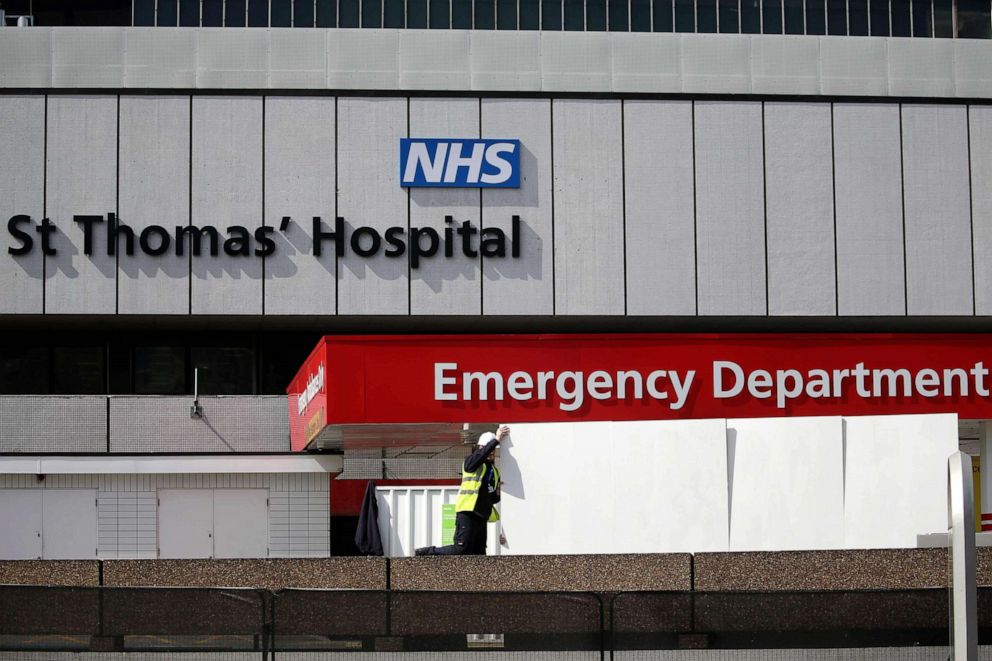 PHOTO: A staff member places screens to shield ambulances at the emergency department of St Thomas' Hospital in central London on April 7, 2020, where U.K. Prime Minister Boris Johnson is in intensive care with symptoms of novel coronavirus infection.