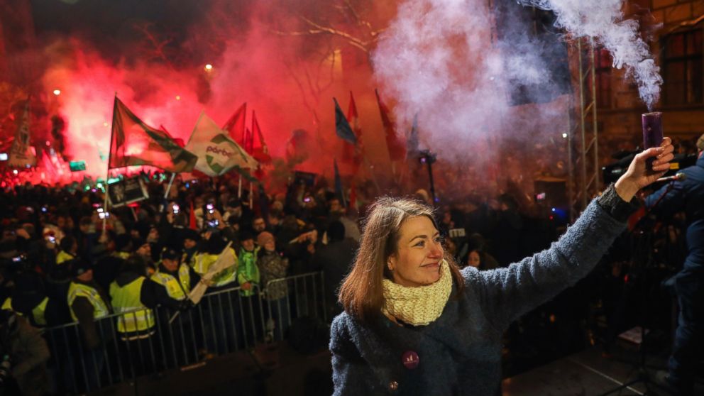 Vice-chairperson of Momentum party Anna Donath holds up a smoke grenade during an anti-government protest in the downtown of Budapest, Hungary, Sunday, Dec. 16, 2018. (Balazs Mohai/MTI via AP)