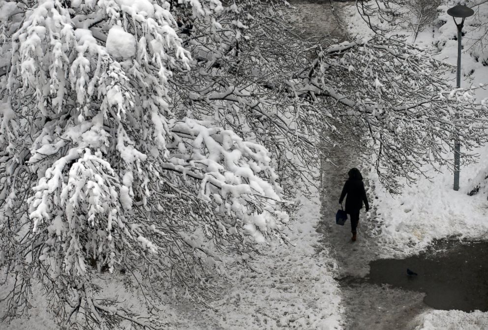 A woman walks through a snow covered park in Belgrade, Serbia, Monday, Dec. 17, 2018.