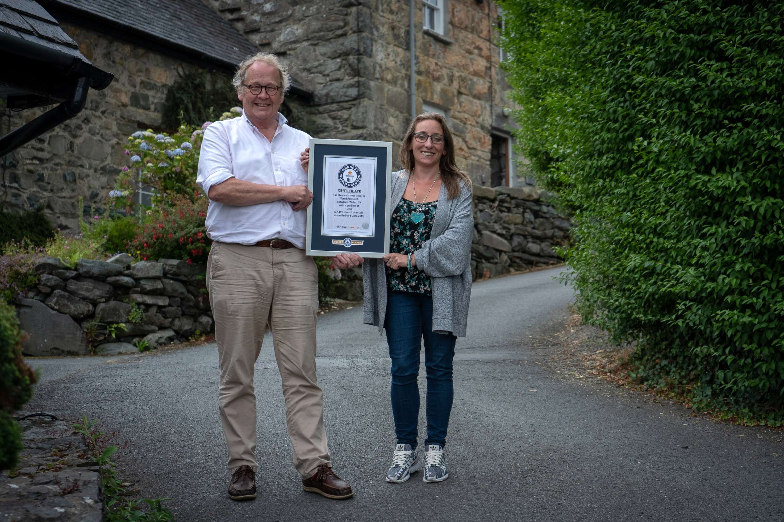 PHOTO: Gwyn Headley and Sarah Badhan, stand on Ffordd Pen Llech with a certificate from Guinness World Records, confirming that the road is the steepest street in the world, in the seaside town of Harlech, North Wales.