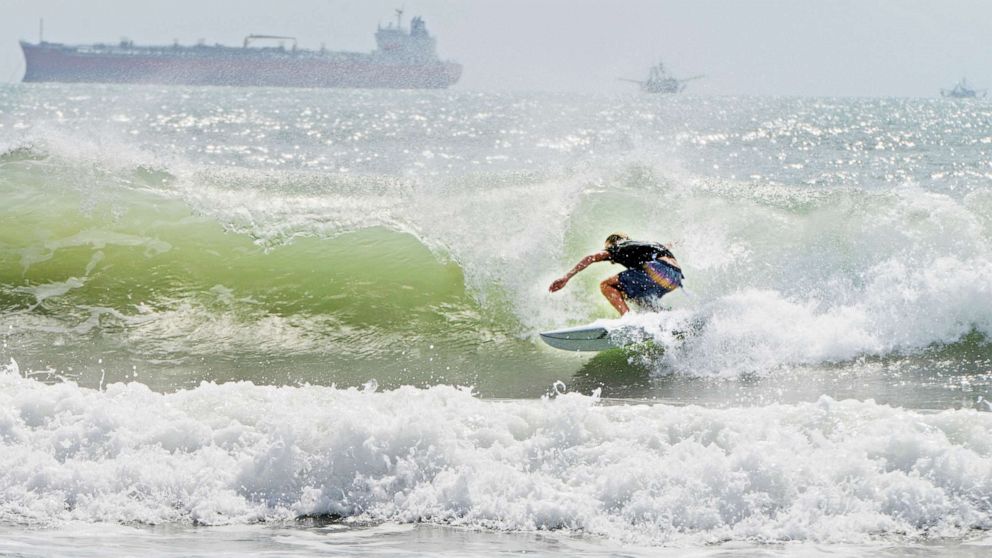 PHOTO: A surfer catches a barrel ride, July 24, 2020, as swell waves approach the coast of South Padre Island, Texas, due to Tropical Storm Hanna approaching the Texas Gulf Coast.