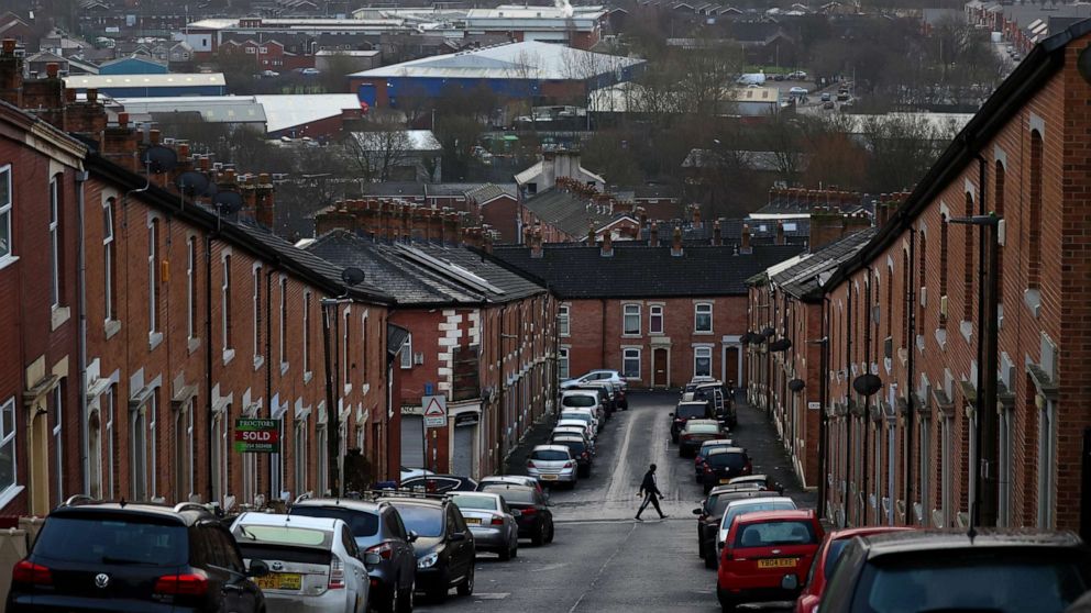 PHOTO: A person walks across a street lined with terraced housing in Blackburn, Lancashire county, northwestern England, on Jan. 17, 2022.