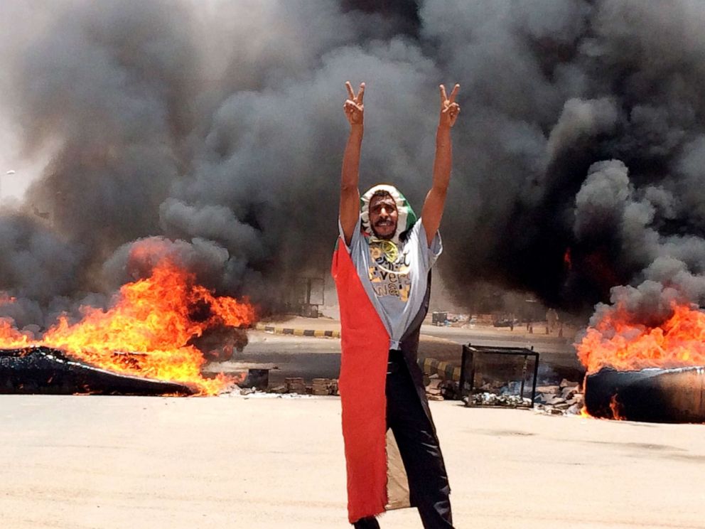 PHOTO: In this June 3, 2019, file photo, a protester flashes the victory sign in front of burning tires and debris near Khartoum's army headquarters, in Khartoum, Sudan.