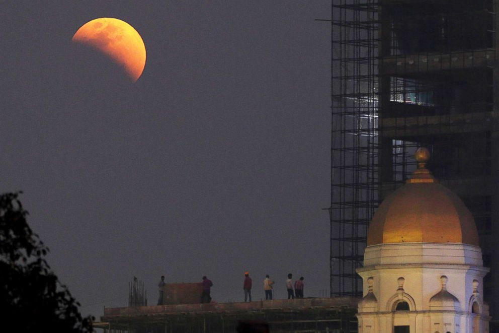 PHOTO: People watch the super moon and full eclipse develop near a heritage building in Calcutta, Eastern India, Jan. 31, 2018.