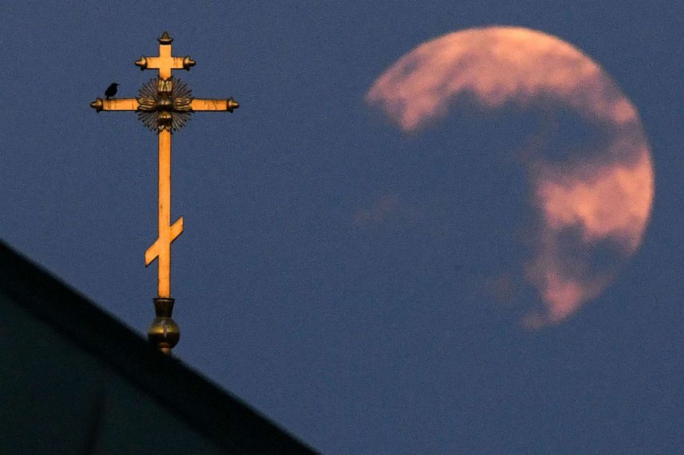 PHOTO: The closest supermoon to the Earth, also known as a pink moon, behind the cross on a church in downtown Moscow, April 8, 2020.