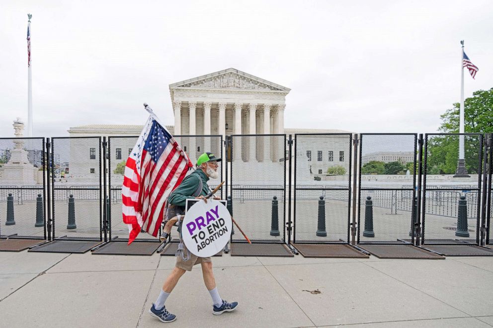 PHOTO: A pro-life protester walks by un-scalable fencing surrounding the U.S. Supreme Court in Washington, D.C., May 5, 2022. 