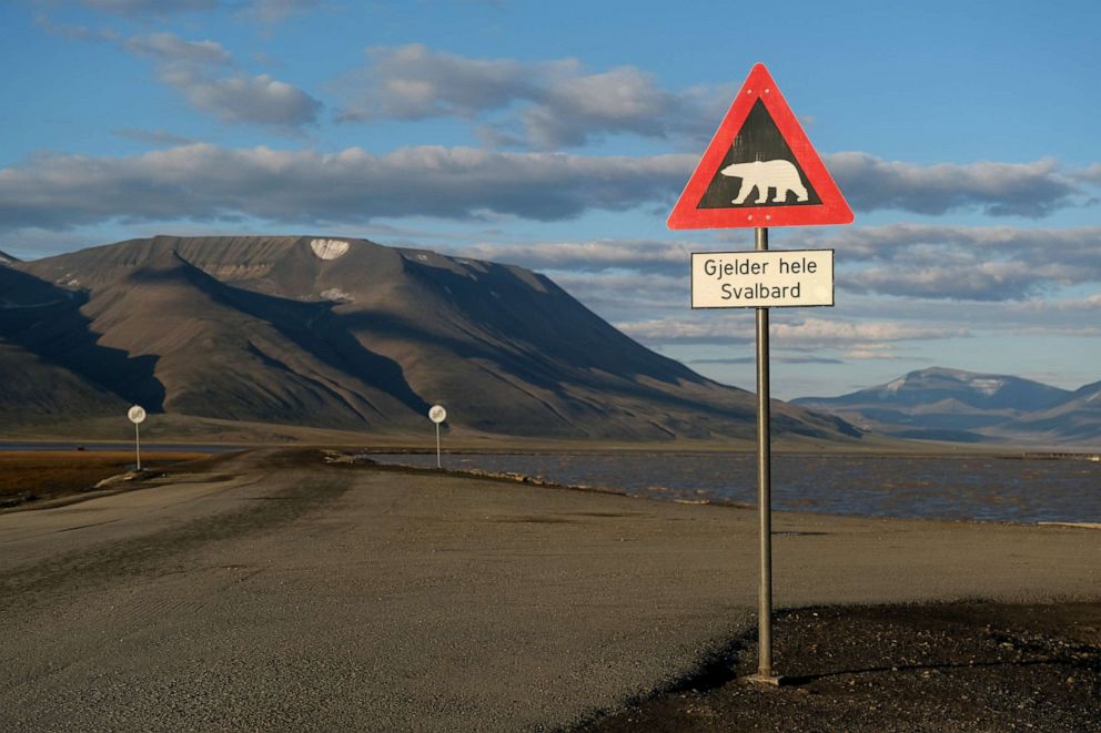 PHOTO: Mountains nearly devoid of snow stand behind a road and a polar bear warning sign during a summer heat wave on Svalbard archipelago, July 29, 2020, near Longyearbyen, Norway. 
