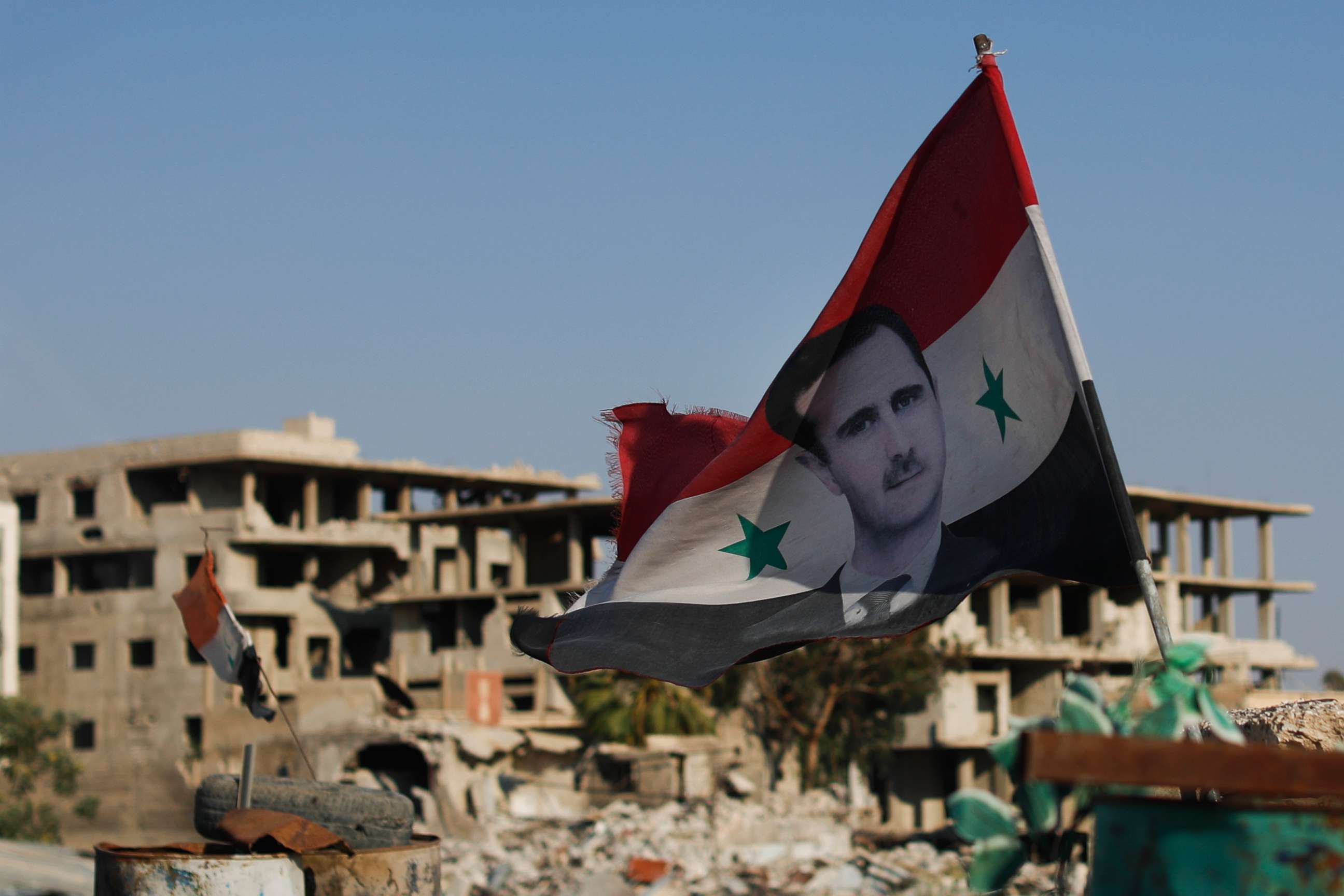 PHOTO: A Syrian national flag with the picture of the Syrian President Bashar Assad hangs at an Army check point, in the town of Douma in the eastern Ghouta region, Syria, July 15, 2018. 