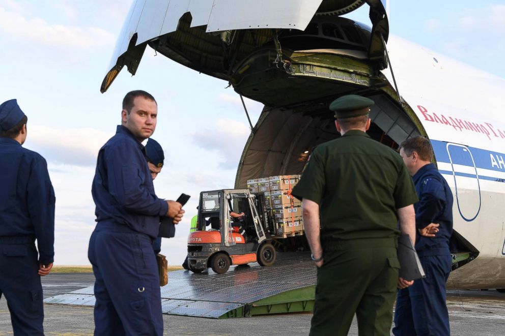 PHOTO: Russian military service personnel watch as supplies are loaded onto an airplane in France, July 20, 2018. France and Russia are jointly delivering humanitarian aid to the former Syrian rebel enclave of Eastern Ghouta.
