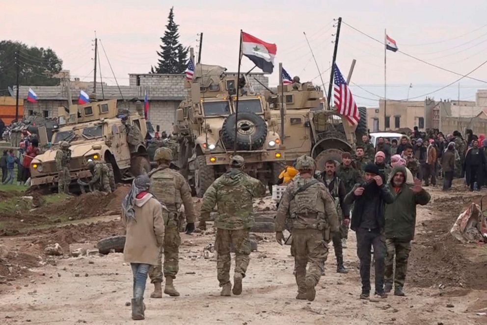 PHOTO: In this frame grab from video, Russians, Syrians and others gather next to an American military convoy stuck in the village of Khirbet Ammu, east of Qamishli city, Syria, Wednesday, Feb. 12, 2020.
