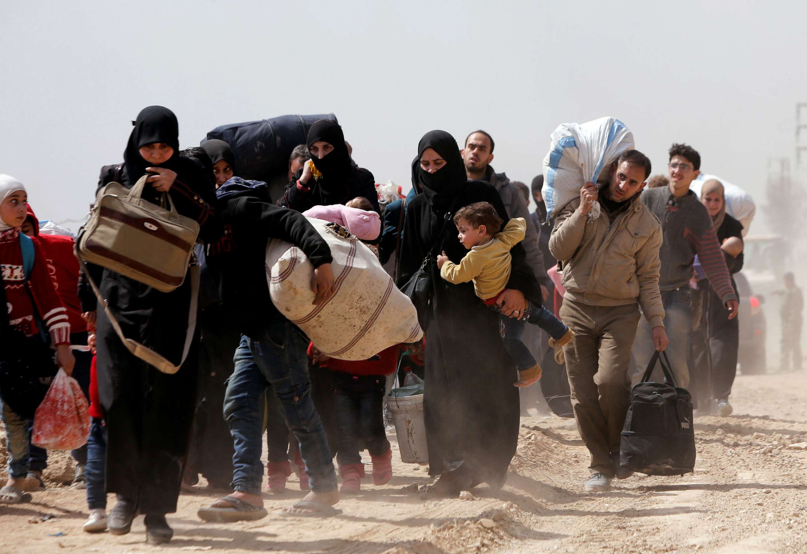 PHOTO: People walk with their belongings as they flee the rebel-held town of Hammouriyeh, in the village of Beit Sawa, eastern Ghouta, Syria, March 15, 2018.