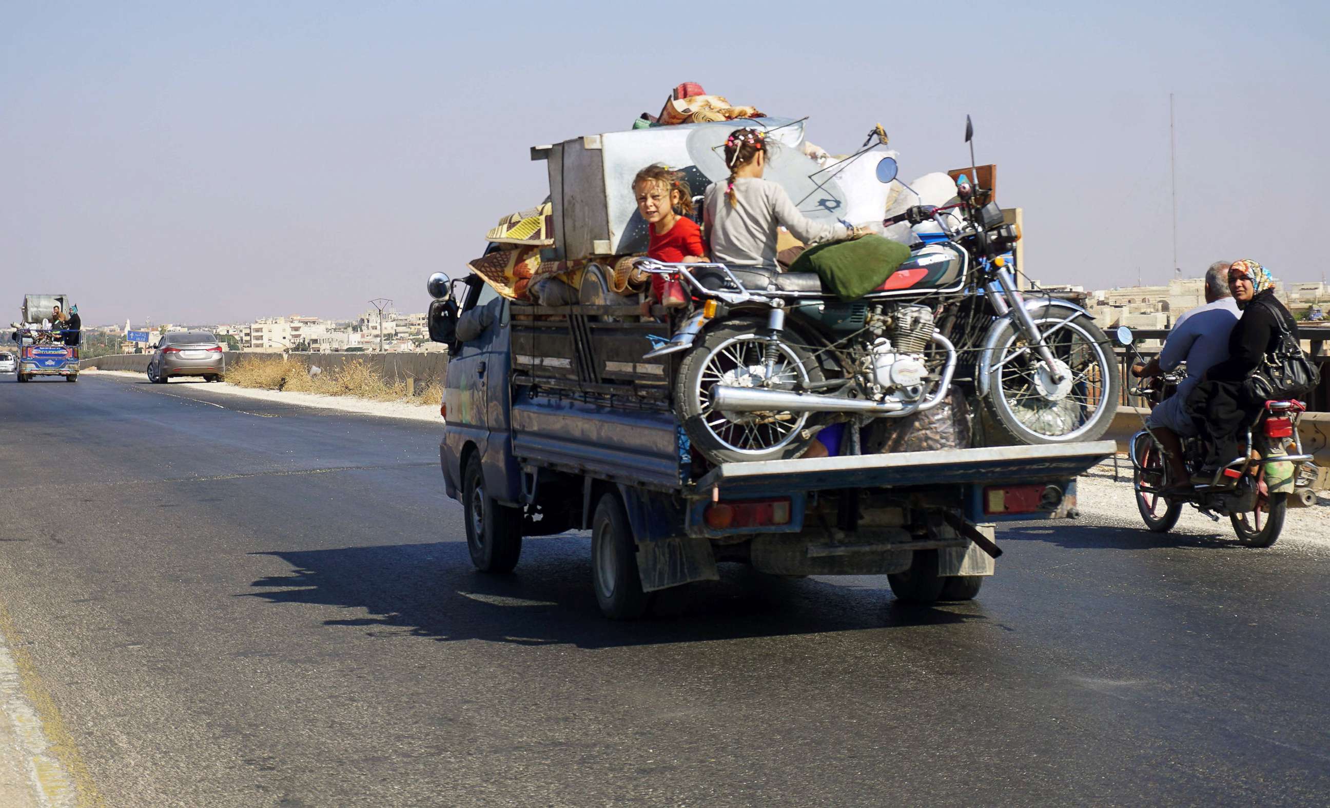 PHOTO: Syrian children riding in the back of a loaded truck drive along the main Damascus-Aleppo highway near the town of Saraqib in Syria's mostly rebel-held northern Idlib province, as families flee the countrysides of Hama and Idlib provinces.