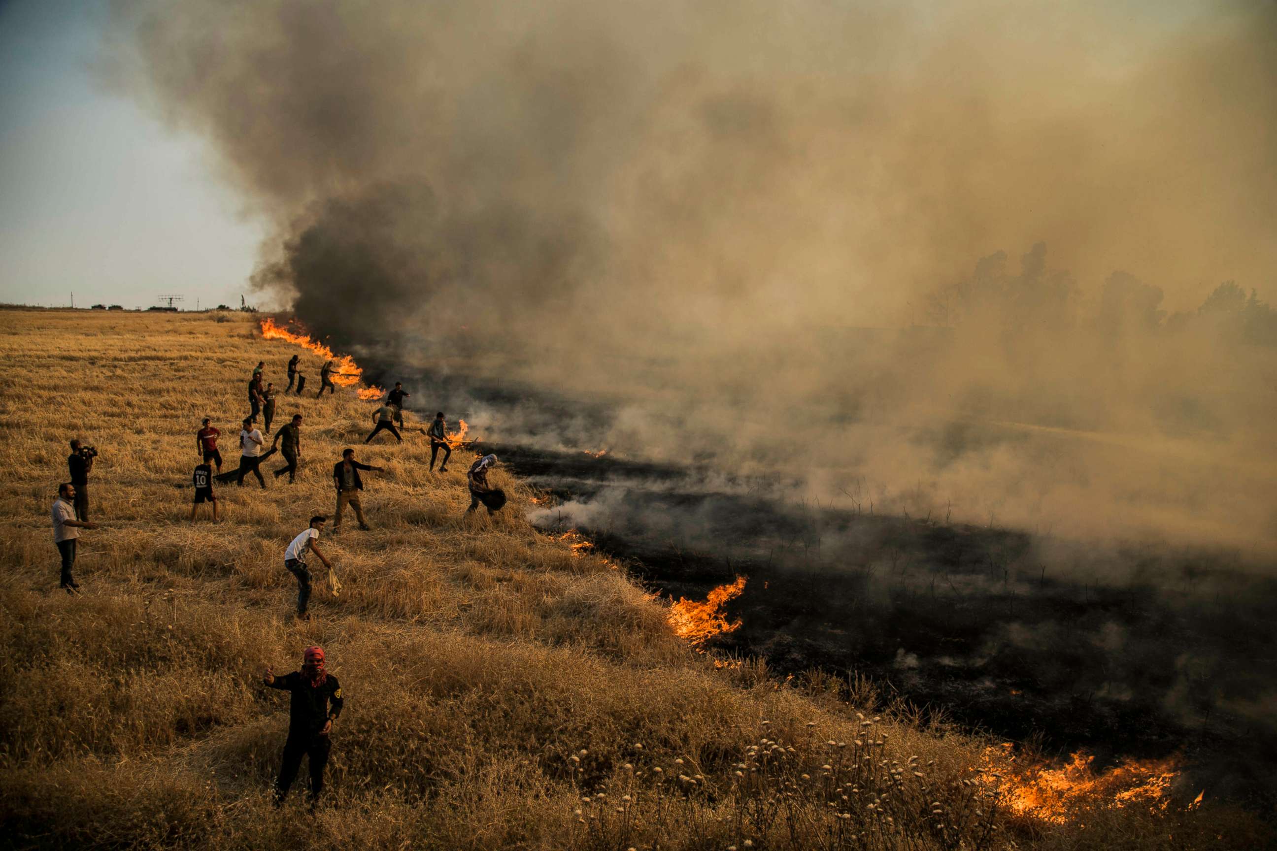 PHOTO: In this June 17, 2019, file photo, people fight the fire in the farmlands surrounding the town of Qamishli in northeastern Syria.