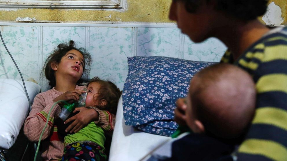 A Syrian girl holds an oxygen mask over the face of an infant at a makeshift hospital following a reported gas attack on the rebel-held besieged town of Douma, in the eastern Ghouta region, on the outskirts of Damascus, Syria, Jan. 22, 2018.