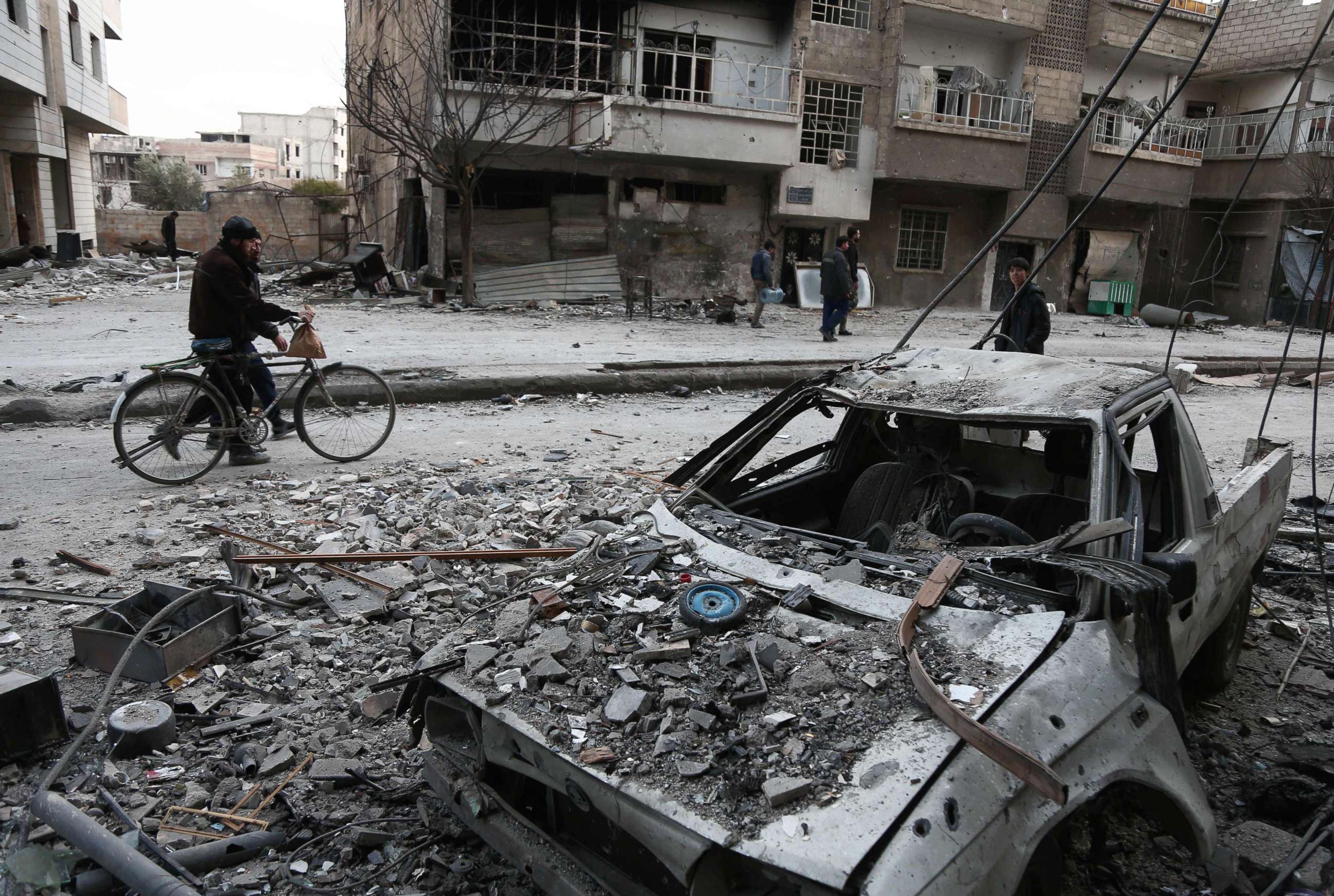 PHOTO: Syrians walk along a street covered in debris in Eastern Ghouta, Syria,  Feb. 25, 2018. 

