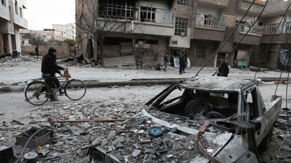 Syrians walk along a street covered in debris in Eastern Ghouta, Syria, Feb. 25, 2018.
