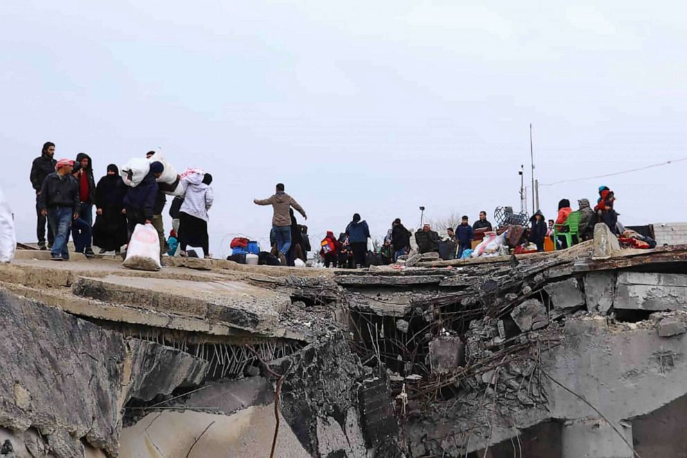 PHOTO: This photo provided on Jan. 30, 2020, shows displaced Syrians fleeing the Syrian military offensive in Idlib province, walking over a destroyed bridge as they arrive in Manbij, north Syria.