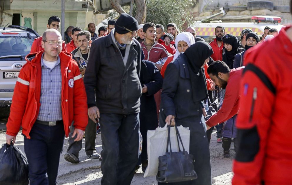 PHOTO: Members of the Syrian Red Crescent escort evacuated civilians from the rebel-held Eastern Ghouta enclave into the government side of the Wafideen checkpoint on the outskirts of Damascus, March 14, 2018.