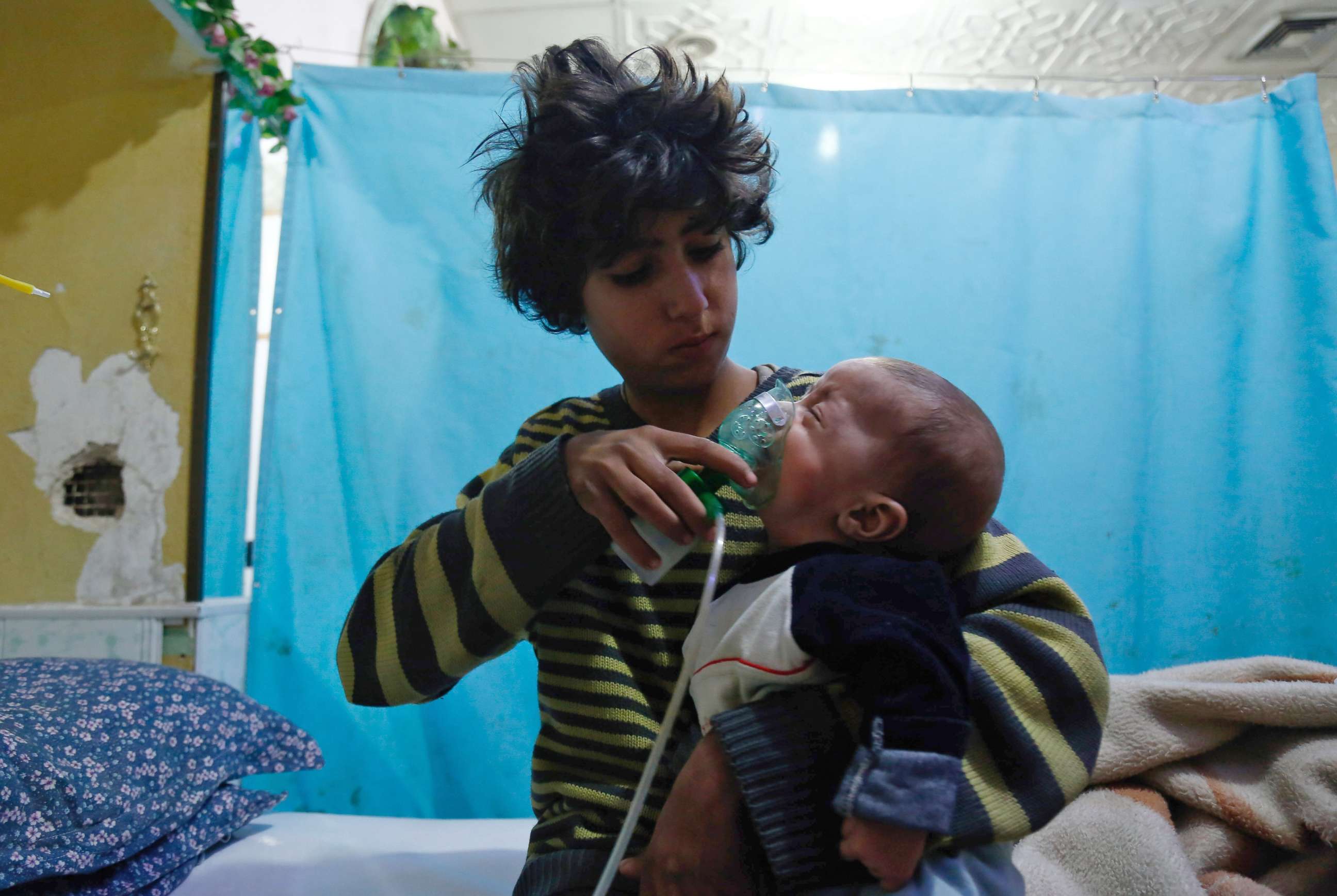 PHOTO: A Syrian boy holds an oxygen mask over the face of an infant at a makeshift hospital following a reported gas attack on the rebel-held besieged town of Douma in the eastern Ghouta region on the outskirts of the capital Damascus on Jan. 22, 2018.