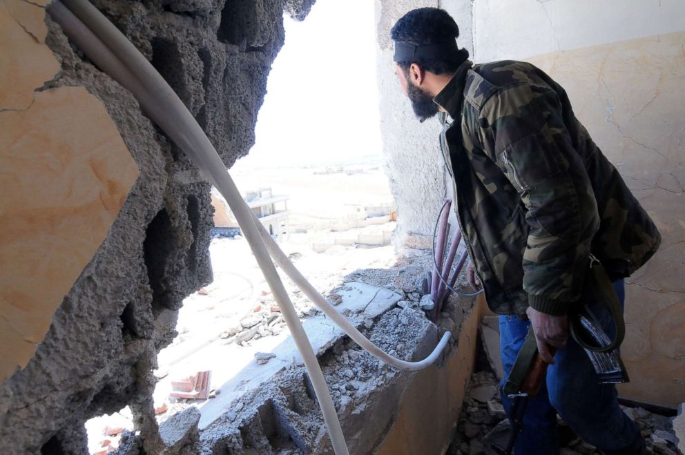 PHOTO: A Syrian rebel is looking of a window during government shelling on their position.