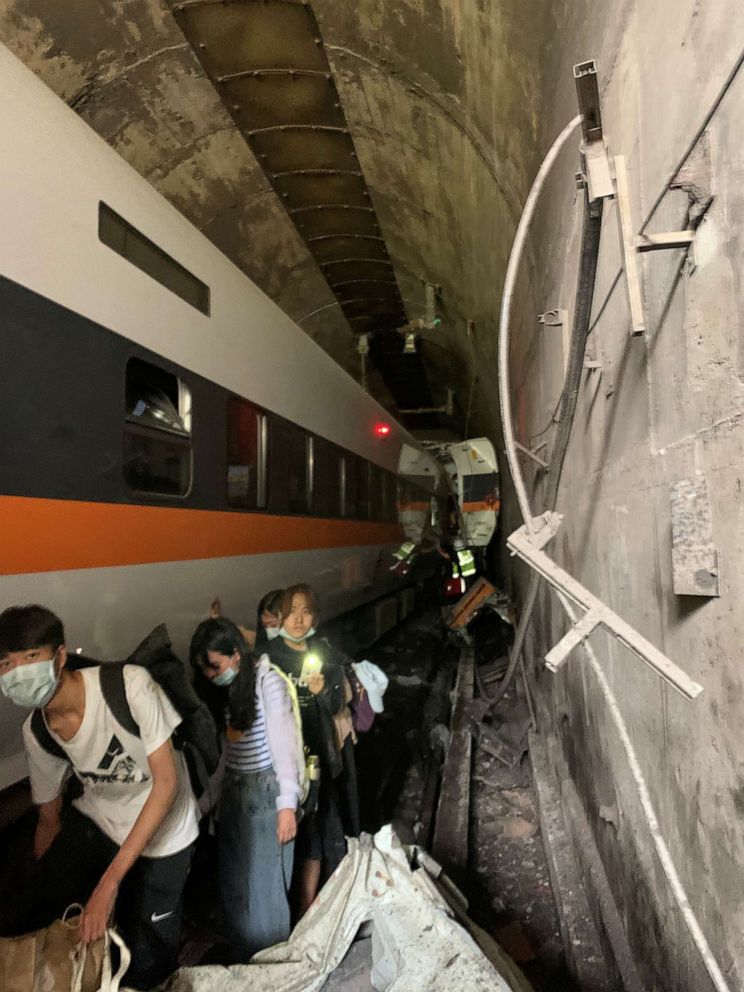PHOTO: People walk next to a train which derailed in a tunnel north of Hualien, Taiwan April 2, 2021, in this handout image provided by Taiwan's National Fire Agency. 
