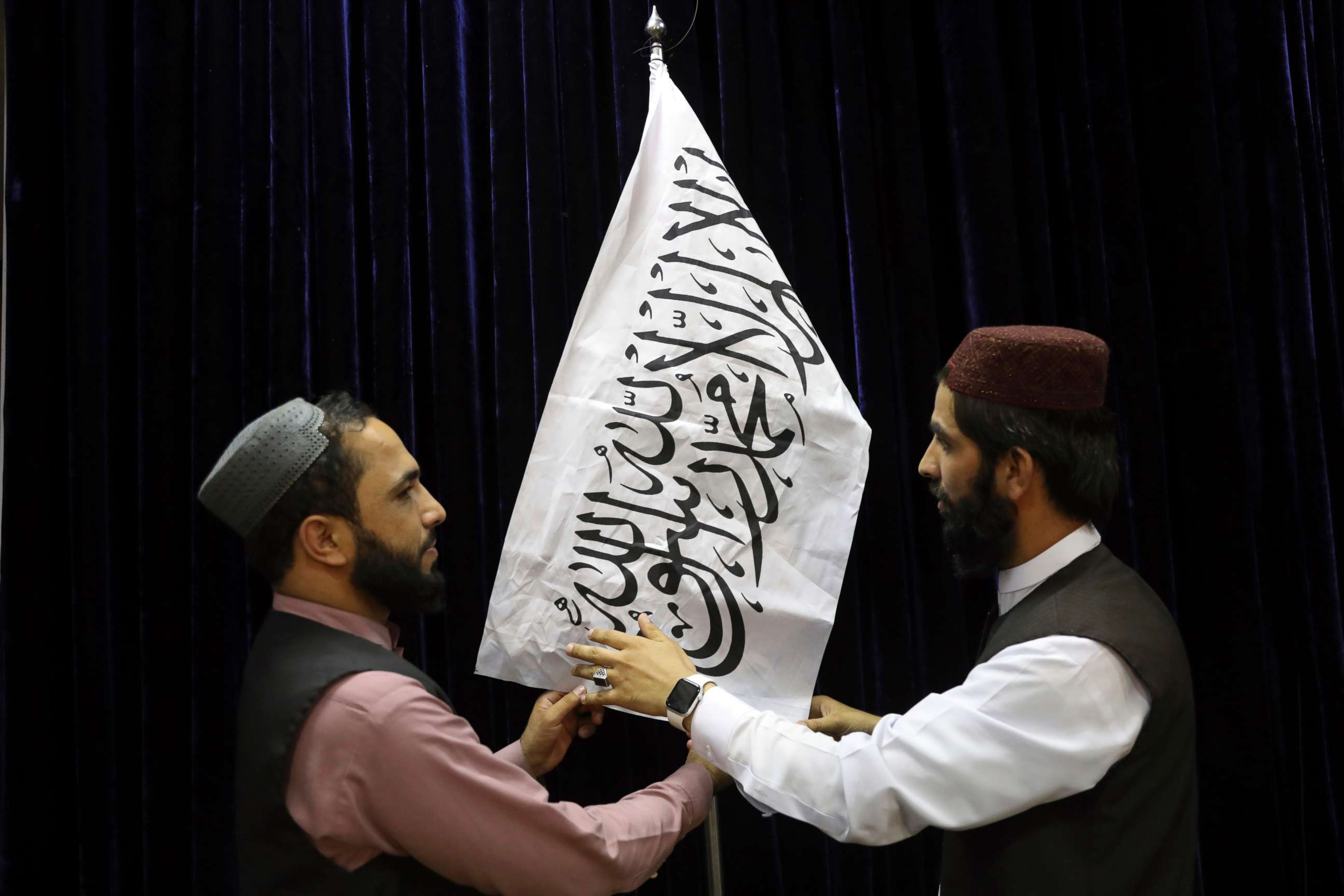 PHOTO: Taliban officials arrange a Taliban flag, before a press conference by Taliban spokesman Zabihullah Mujahid, at the Government Media Information Center, in Kabul, Afghanistan, Aug. 17, 2021.