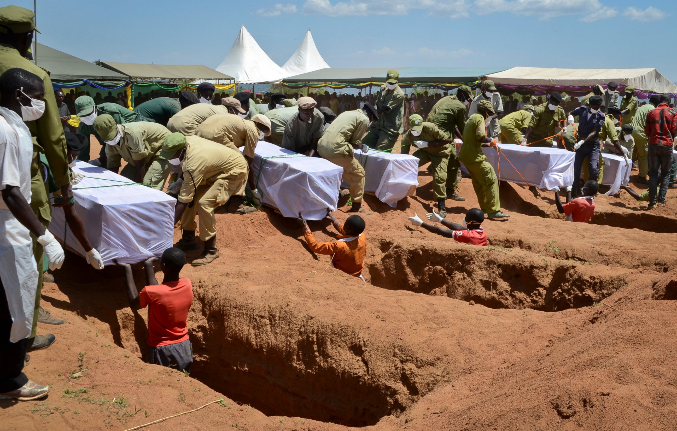 PHOTO: Coffins of some of the victims of the MV Nyerere passenger ferry capsizing are laid into graves during a mass burial ceremony on Ukara Island, Tanzania, Sunday, Sept. 23, 2018.