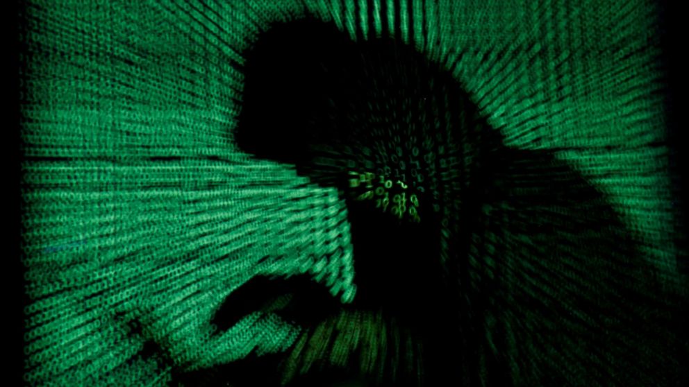 PHOTO: A hooded man holds a laptop computer as cyber code is projected on him in this illustration picture taken on May 13, 2017.