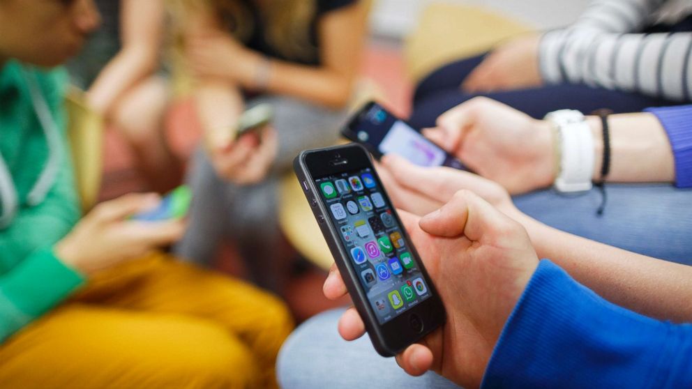 A group of students play with their smartphones in a stock photo.